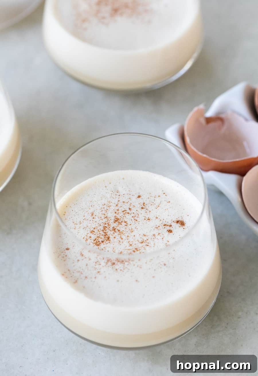 A close-up view of creamy homemade eggnog, emphasizing its rich, smooth texture and the wholesome ingredients like real egg yolks and holiday spices used in its preparation.