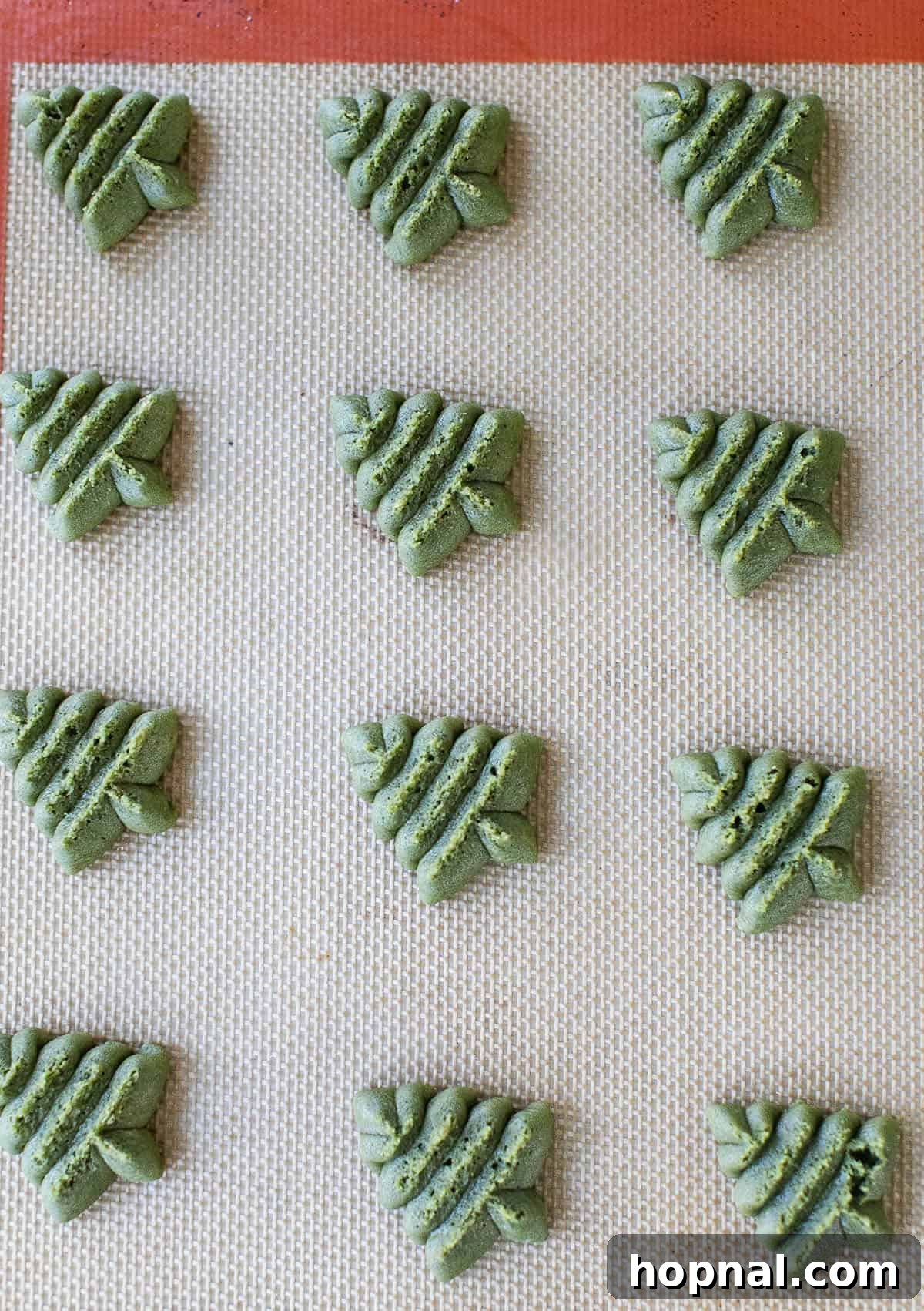 Melt-in-Your-Mouth Spritz Cookies 8 Spritz cookie Christmas trees on a baking sheet, before baking.