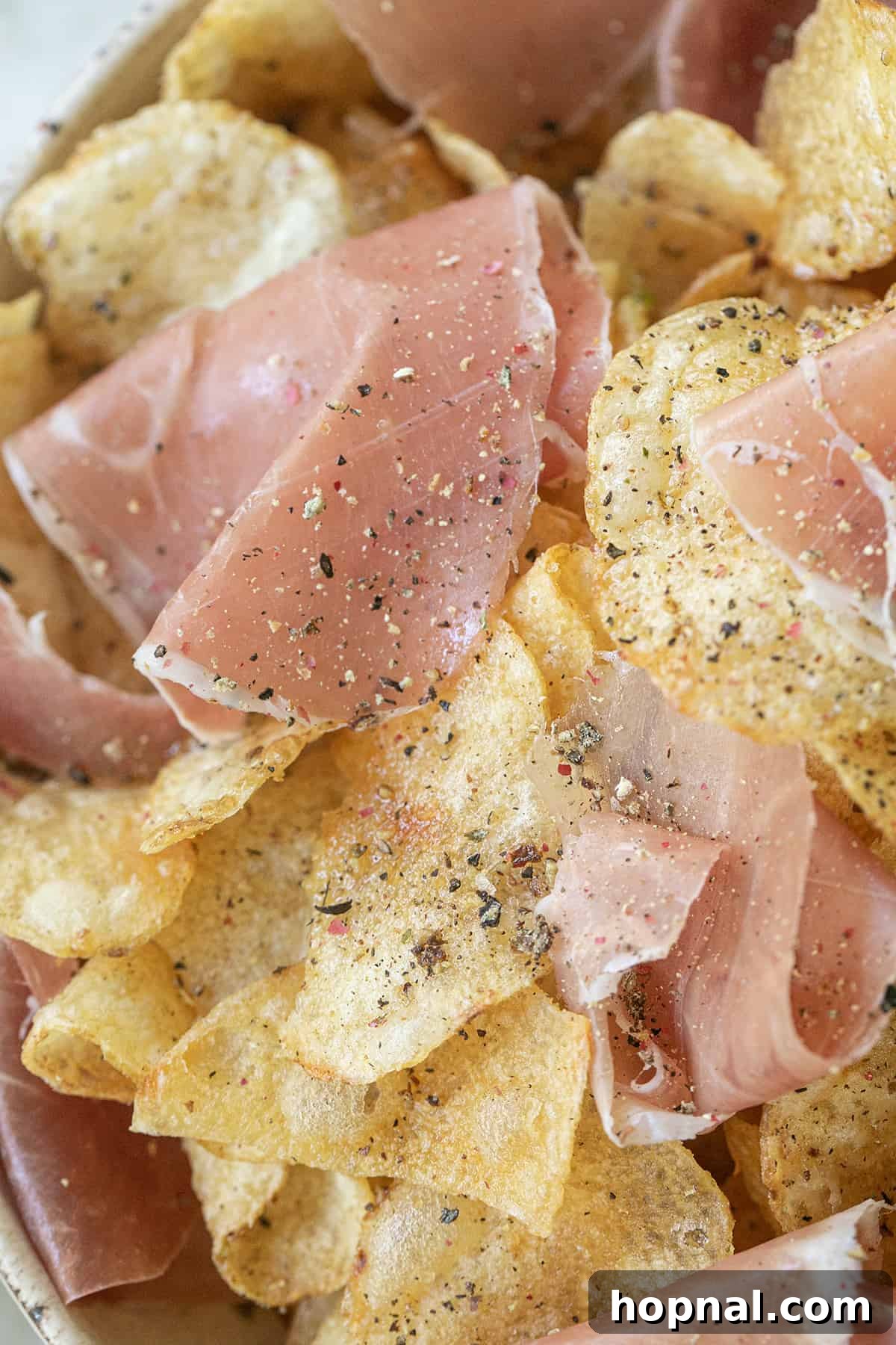 The finished prosciutto and potato chips appetizer, featuring thin slices of cured ham draped over truffle-infused potato chips.