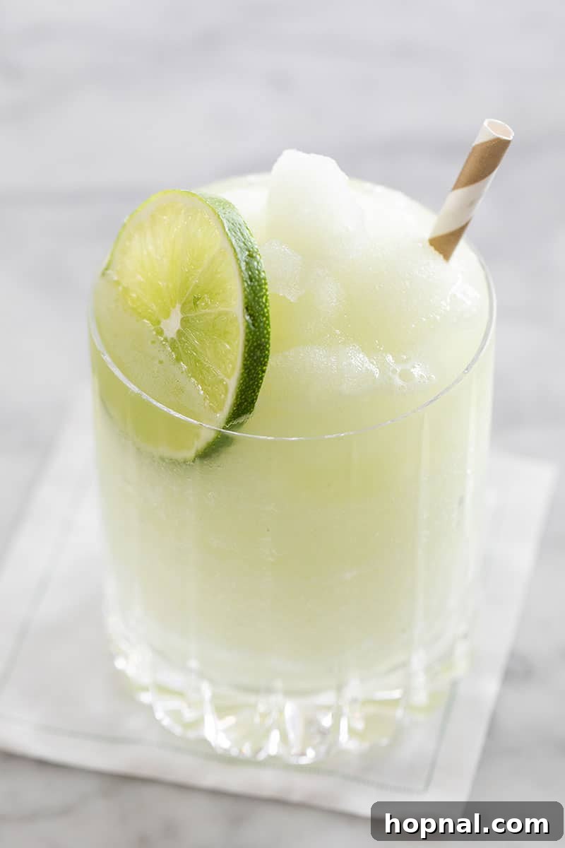 Frosty Frozen Gin and Tonic cocktail garnished with lime and cucumber