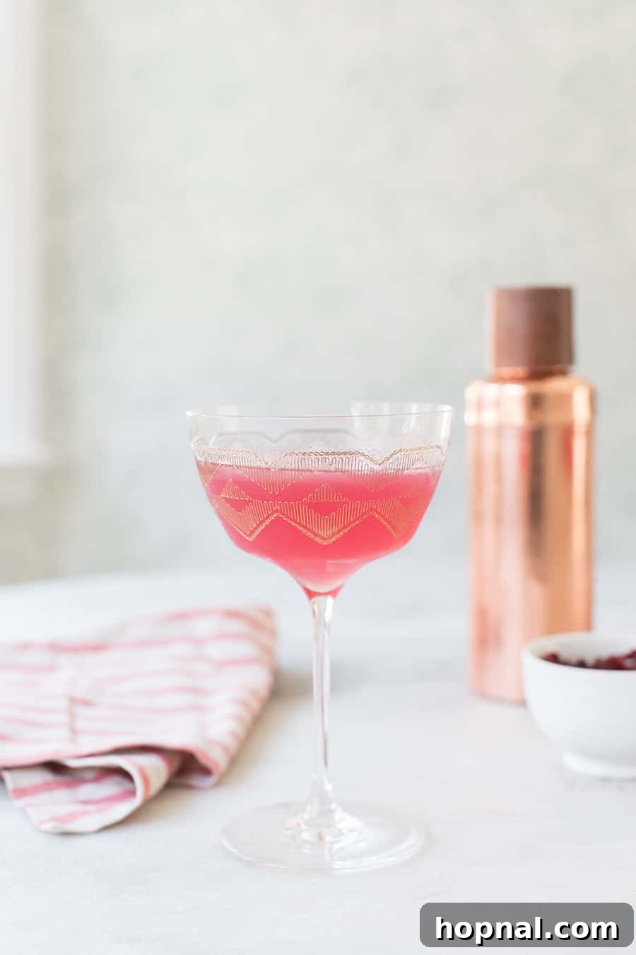 A beautiful pink gin martini, garnished with a delicate flower, perfect for festive occasions.