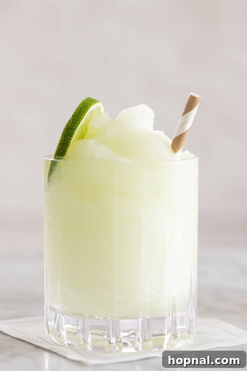 A frosty Frozen Gin and Tonic, topped with lime slices and fresh mint, perfect for cooling down.