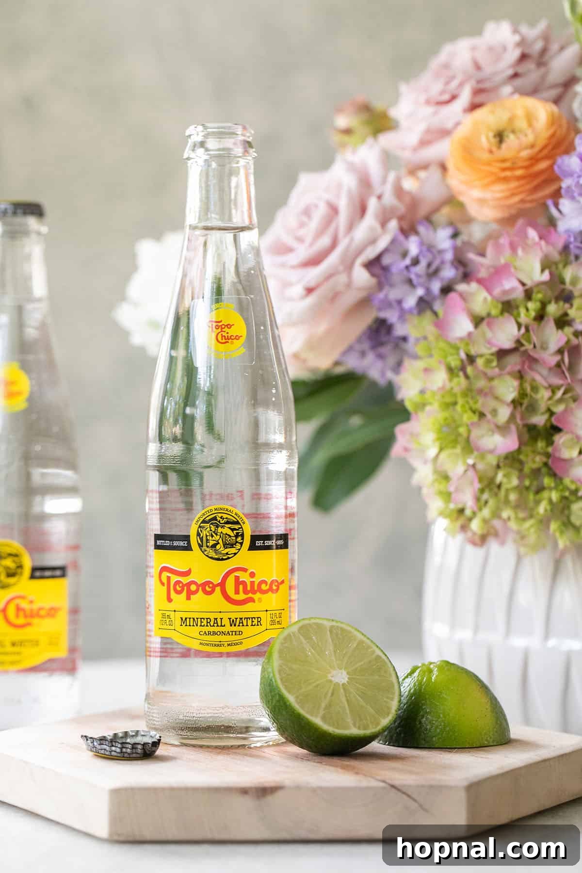 Everything You Need to Know About Topo Chico 3 A glass bottle of Topo Chico with sliced limes beside it
