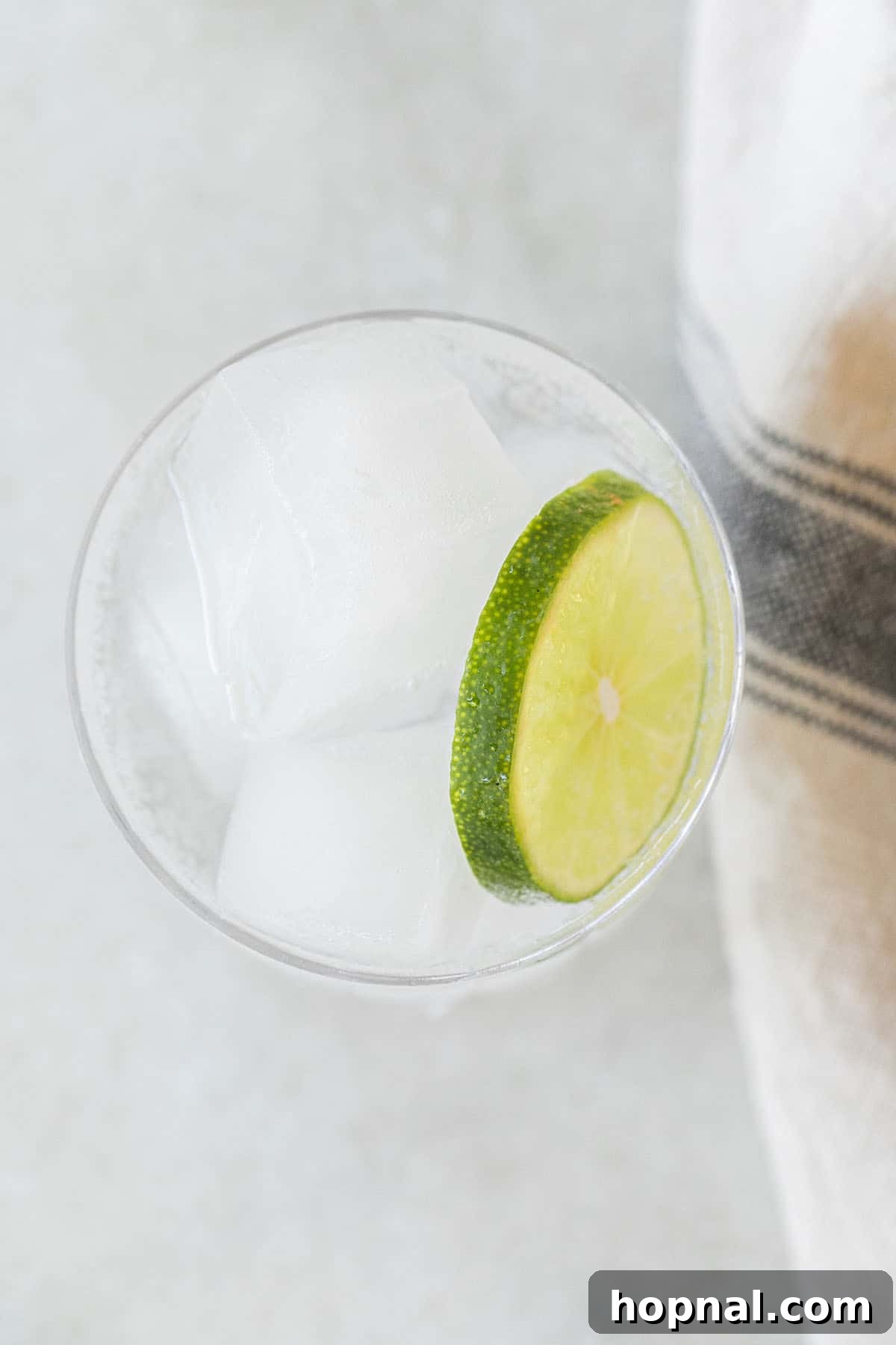 glass of ice and clear liquid with lime slice