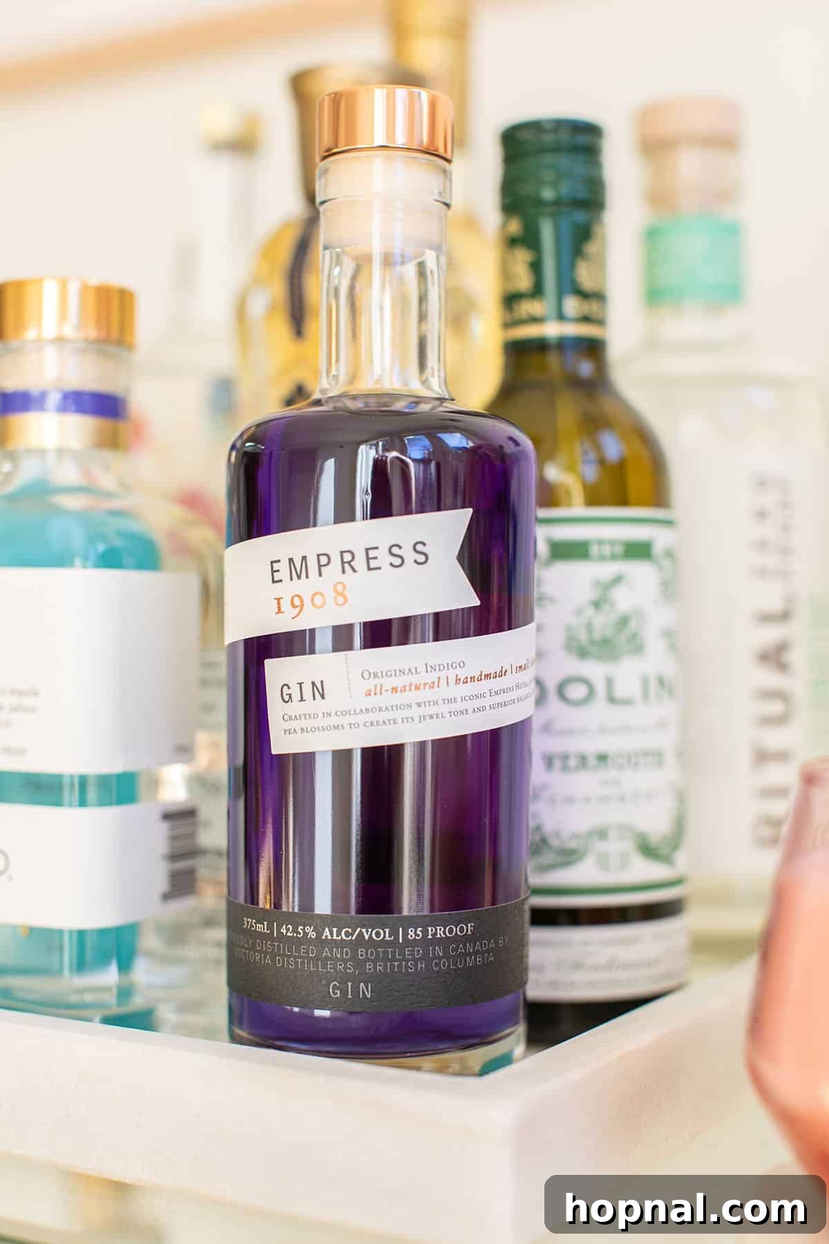 Bottle of Empress 1908 Gin on a stylish bar cart, showcasing its beautiful indigo hue.