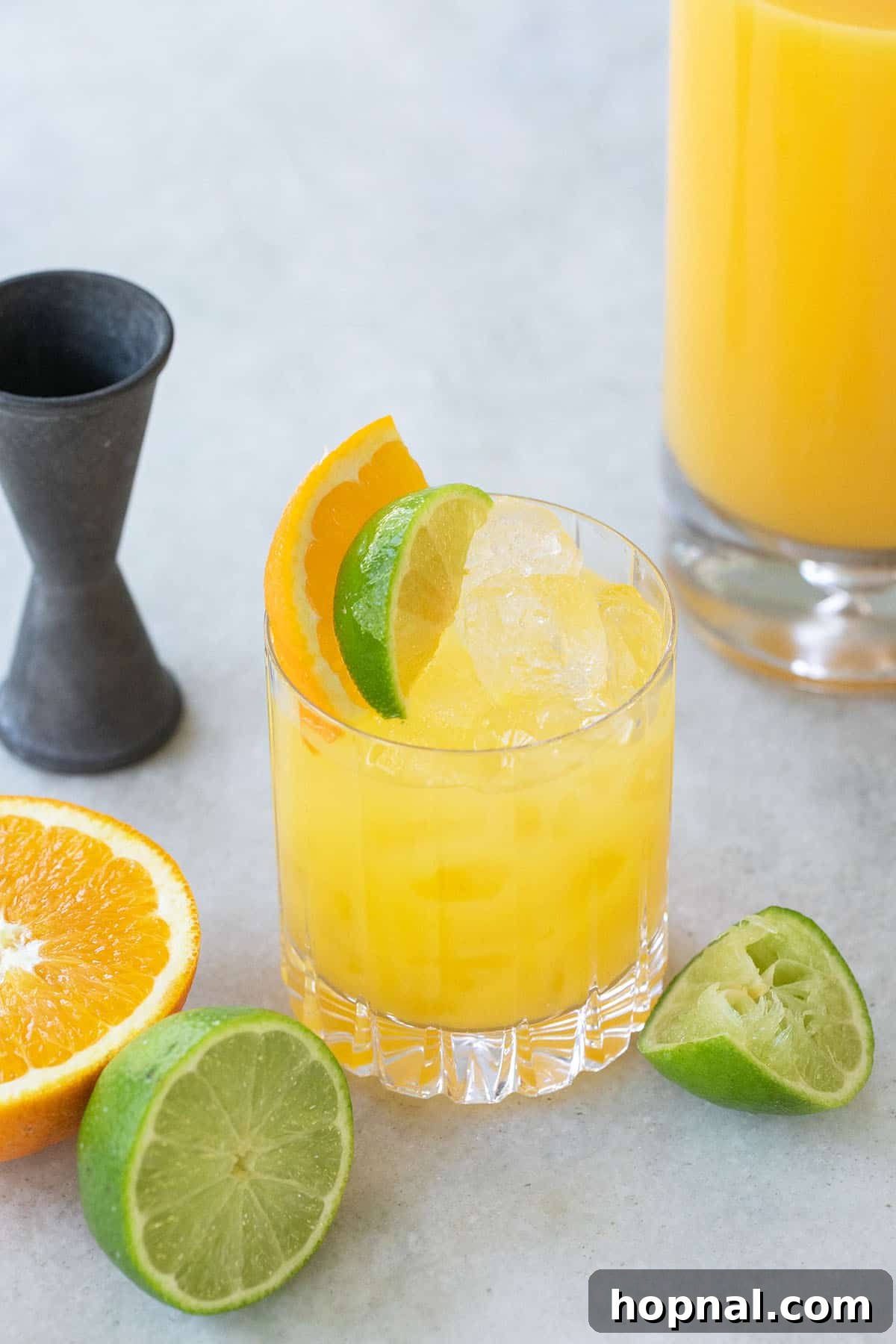 A vibrant Tequila and Orange Juice cocktail, garnished with fresh orange and lime slices, set against a summer backdrop.
