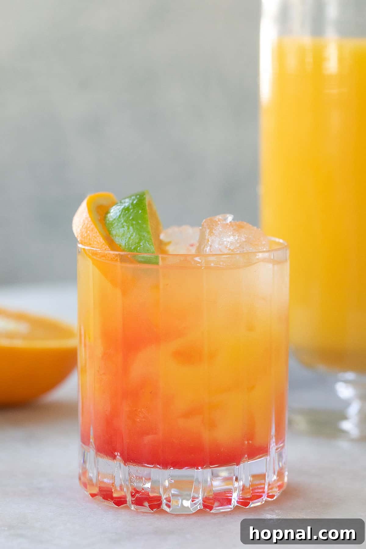 A vibrant Tequila Sunrise cocktail, showcasing the distinct layers of tequila, orange juice, and grenadine, garnished with a cherry and an orange slice.