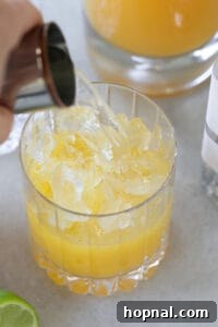 Pouring tequila into a glass with orange juice