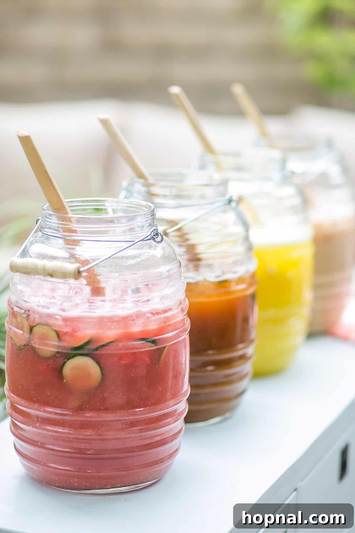 Three different flavors of Agua Fresca: watermelon, hibiscus, and horchata, served in glasses on a tray.