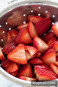 Freshly sliced strawberries on a board.