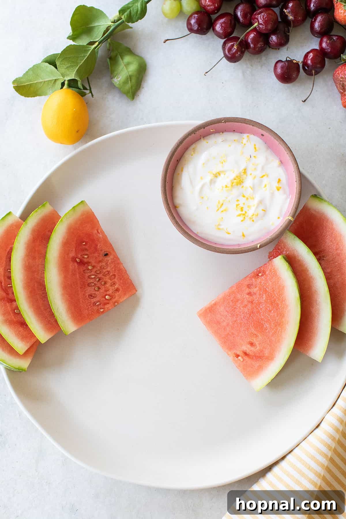 Arranging a colorful fruit platter with watermelon slices, grapes, and small bowls for delicious fruit dips.