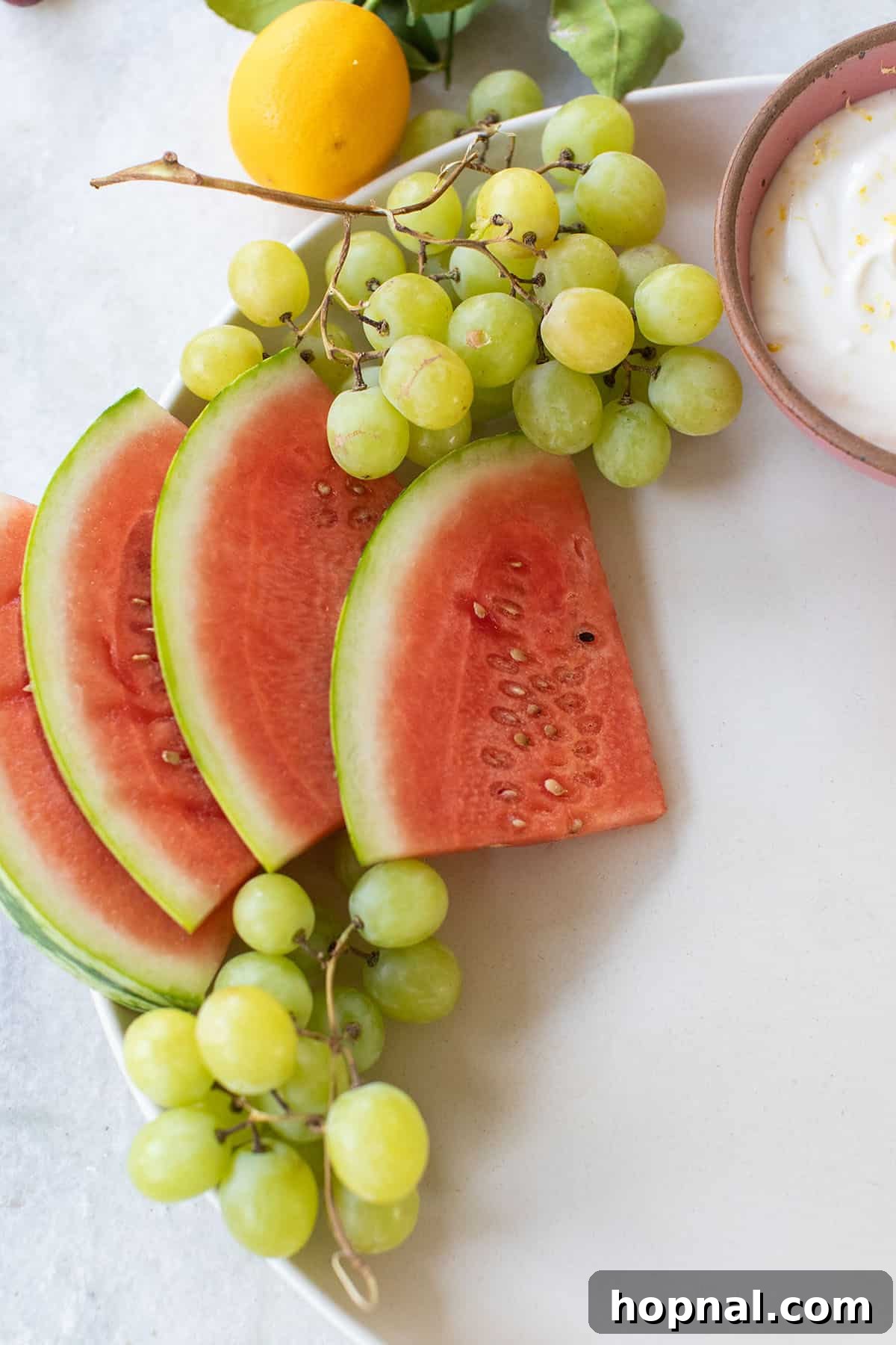 Fresh watermelon wedges and bunches of green grapes ready to be incorporated into a beautiful fruit tray.