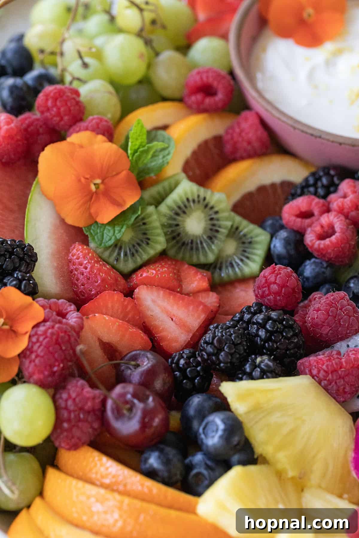 An inviting arrangement of sliced kiwi, blueberries, golden pineapple chunks, orange slices, and delicate edible flowers.