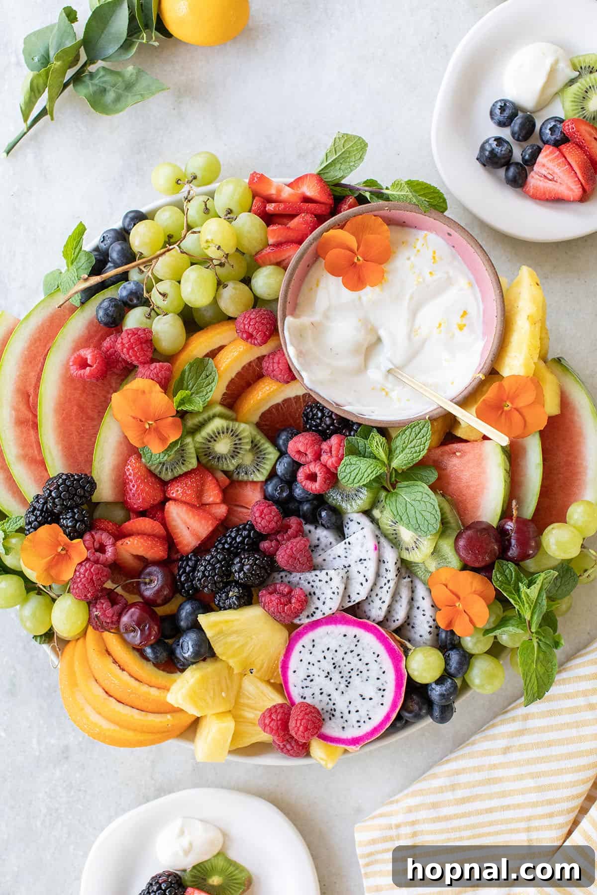 A refreshing summer fruit tray featuring bright kiwi slices, juicy orange wedges, and aromatic fresh mint sprigs for garnish.