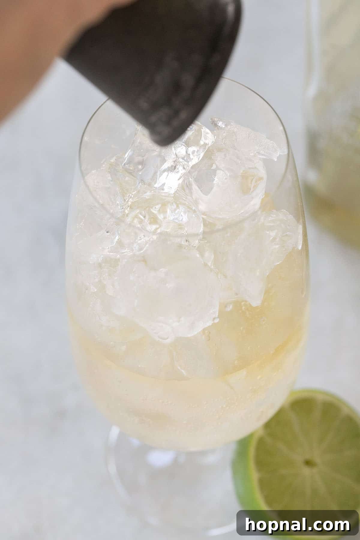 Whiskey Ginger Sparkle 3 Image demonstrating the pouring of whiskey into a glass filled with ginger ale and ice