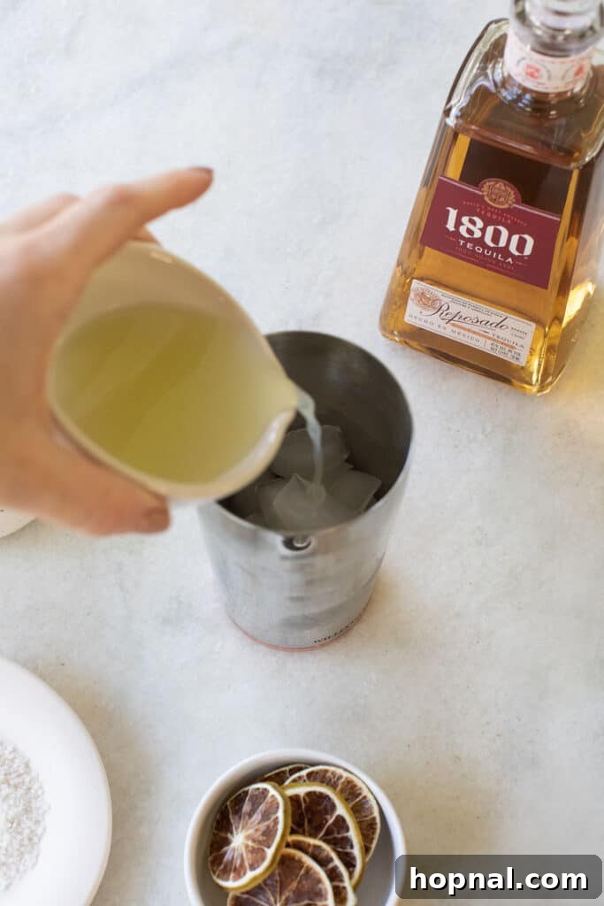 Adding fresh lime juice into a cocktail shaker with other ingredients.