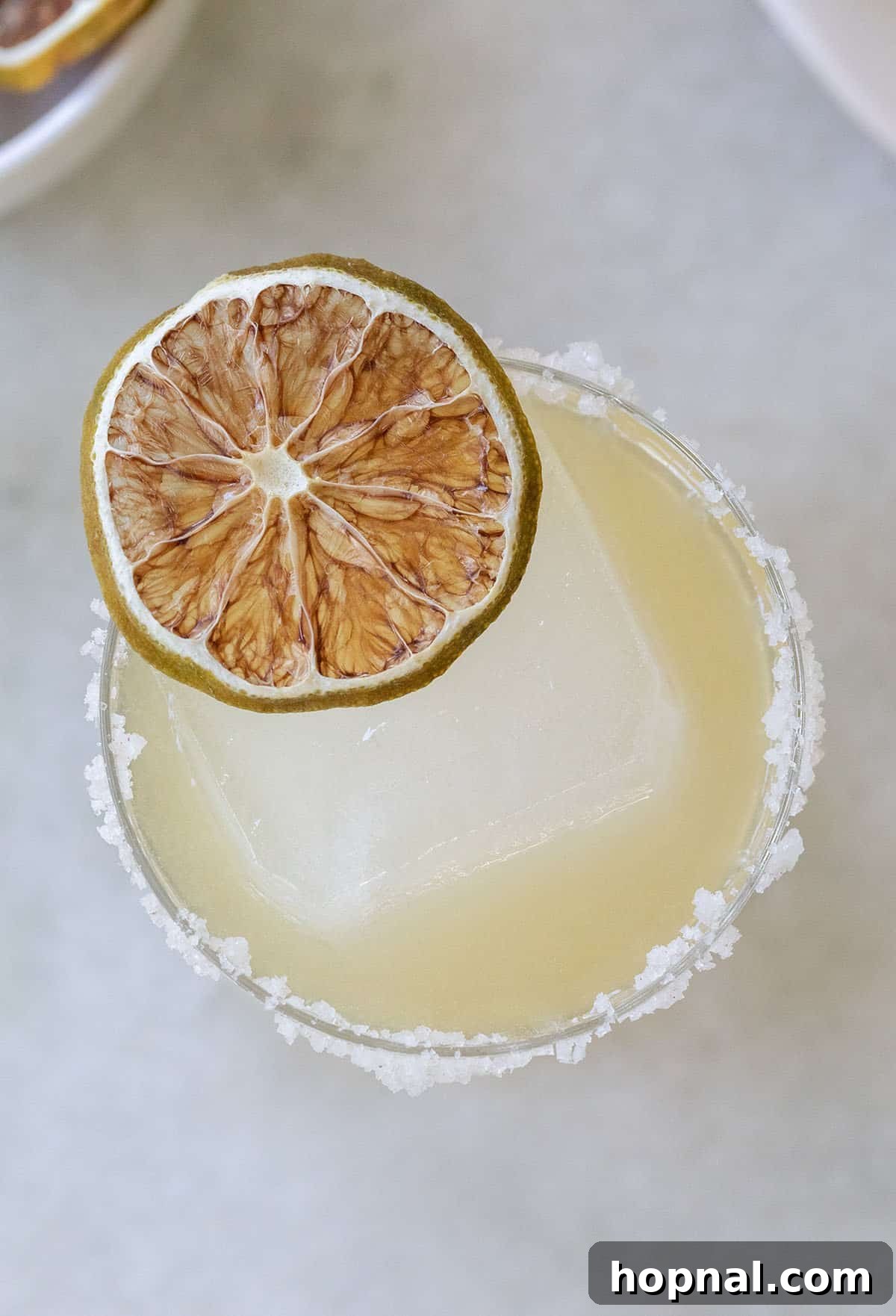 close-up of a golden margarita recipe with gold tequila, garnished with a lime slice and a salted rim.