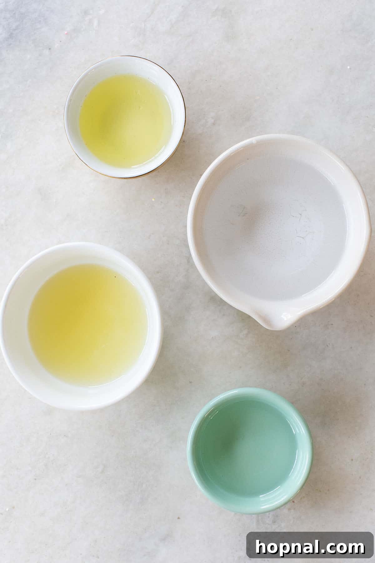 Essential ingredients for a Vodka Sour displayed in elegant bowls: premium vodka, freshly squeezed lemon juice, a separated egg white, and homemade simple syrup.