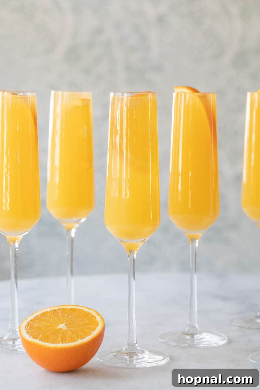 A freshly prepared mimosa in a flute, garnished with an orange slice