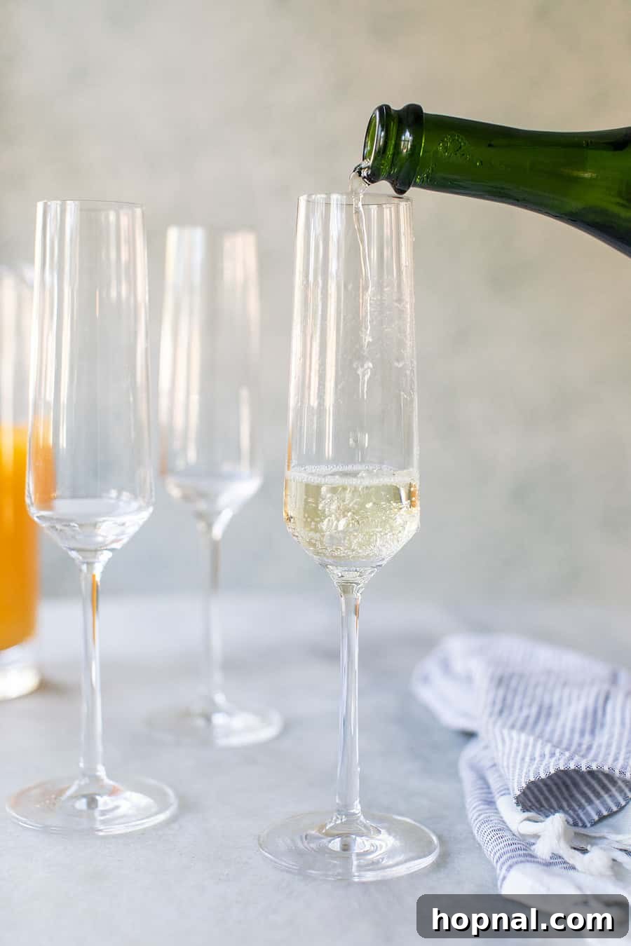Hand pouring Champagne into a flute, with golden liquid shimmering