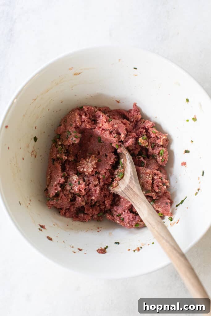 Simple Meatball Bites 5 Hand mixing ground meat and spices in a bowl to form appetizer meatballs.