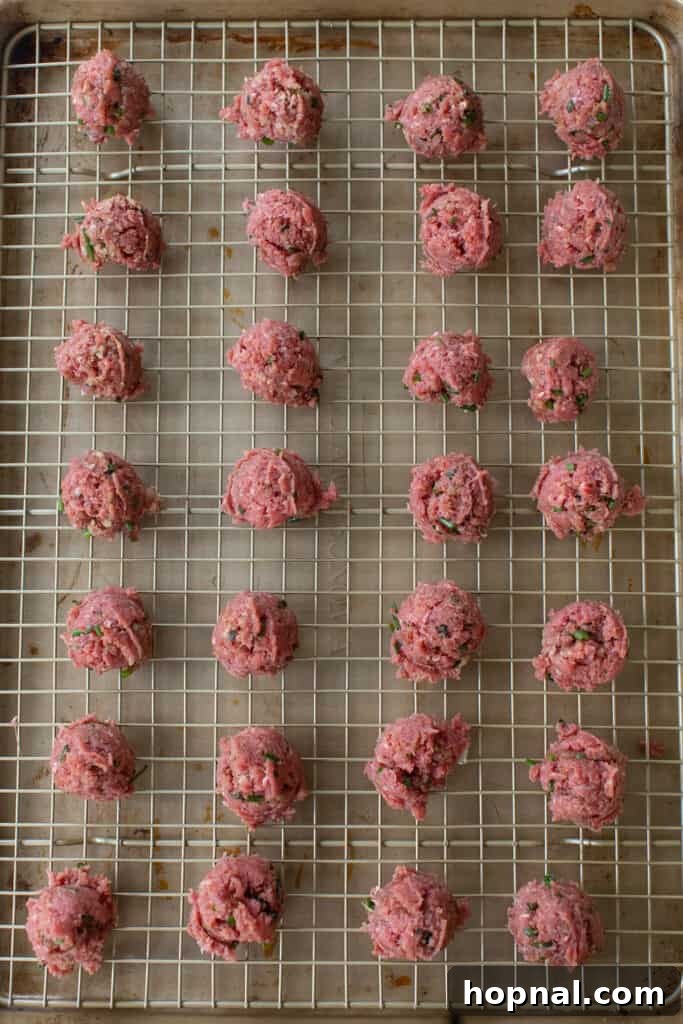 Simple Meatball Bites 7 Rows of perfectly portioned mini meatballs on a baking sheet, ready for the oven.