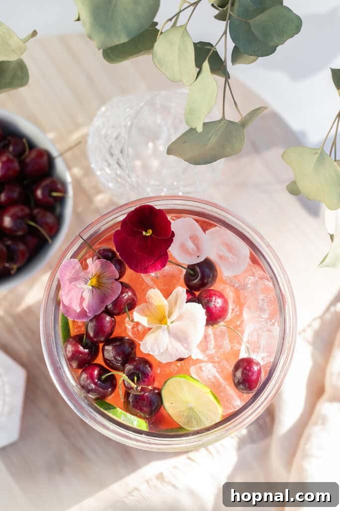 Refreshing cherry punch recipe with gin in a large glass dispenser, perfect for parties