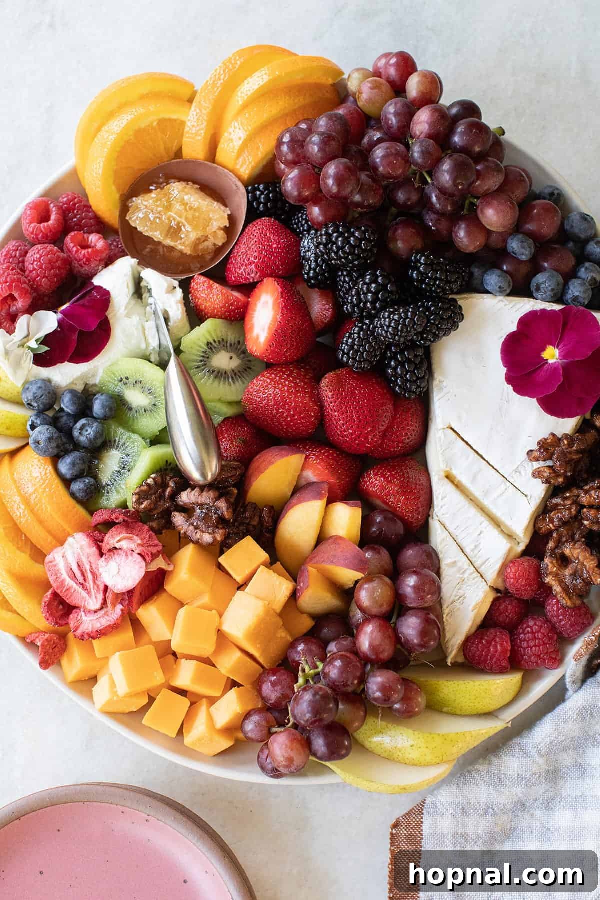 Elegant Cheese and Fruit Board 2 Beautiful fruit and cheese platter featuring a variety of fresh sliced fruits, artisan cheeses, and crunchy nuts, artfully arranged on a wooden board.