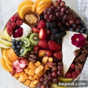 Fruit and cheese platter with fresh strawberries, kiwi, oranges, and more fruit, beautifully arranged.