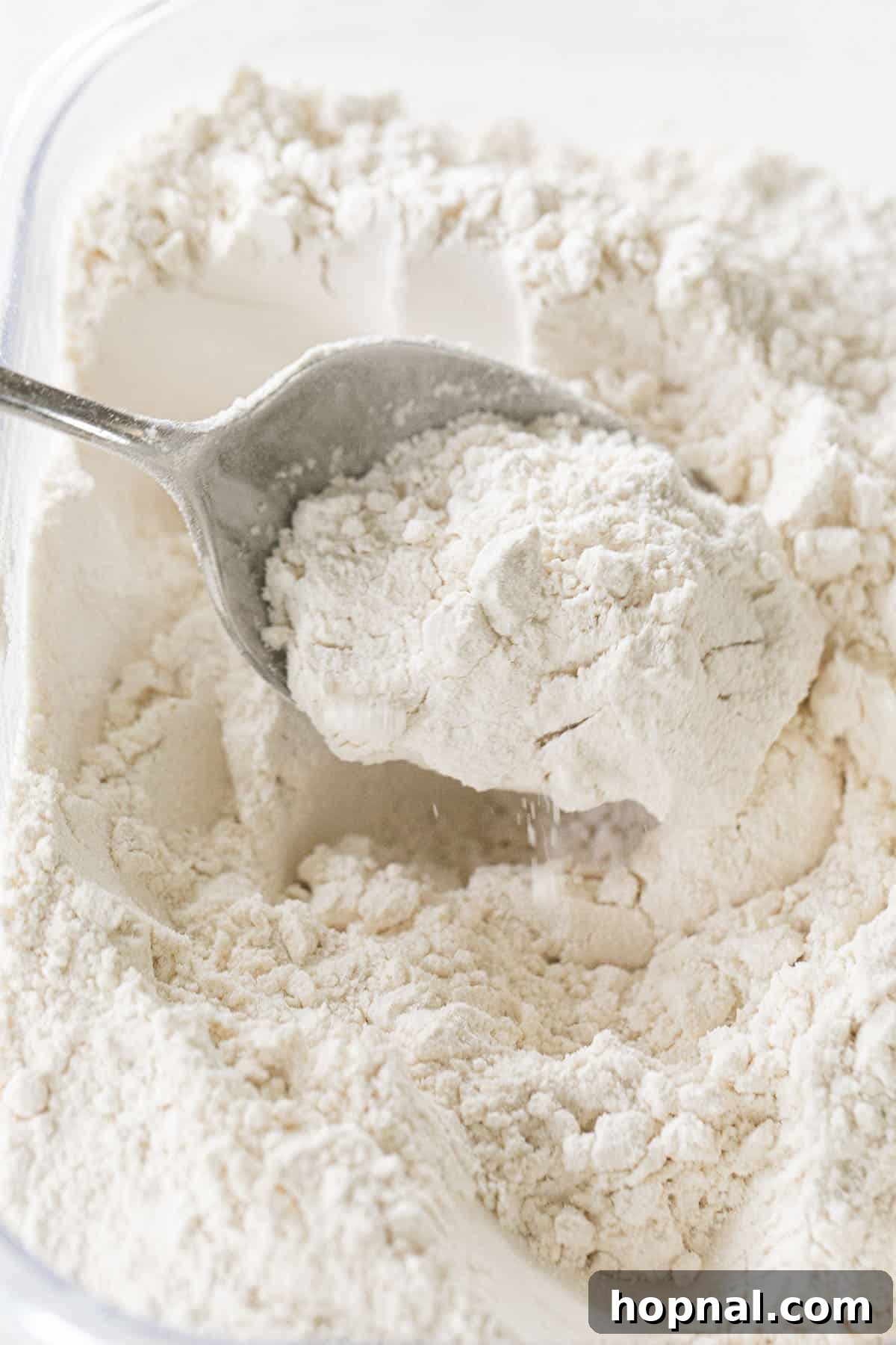 Unlock Fluffy Cakes: Cake Flour Recipes 10 A hand fluffing flour with a spoon, demonstrating the light texture of cake flour or a sifted mixture, crucial for airy cakes.
