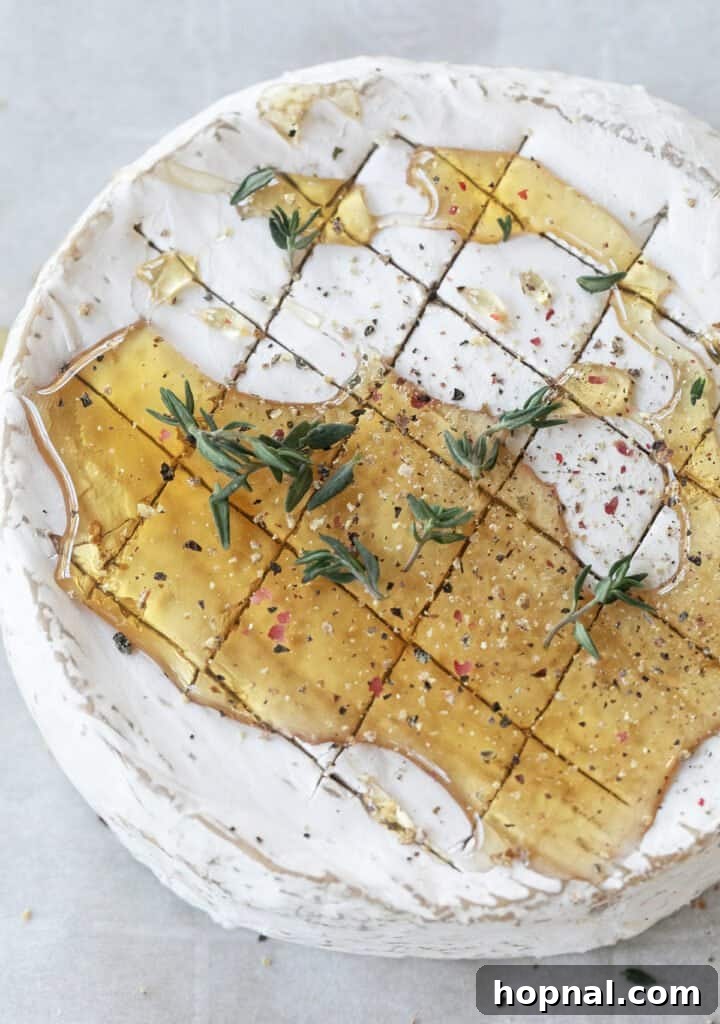 Effortless Baked Brie 5 Brie cheese drizzled with golden honey and garnished with fresh thyme leaves, pre-baking.