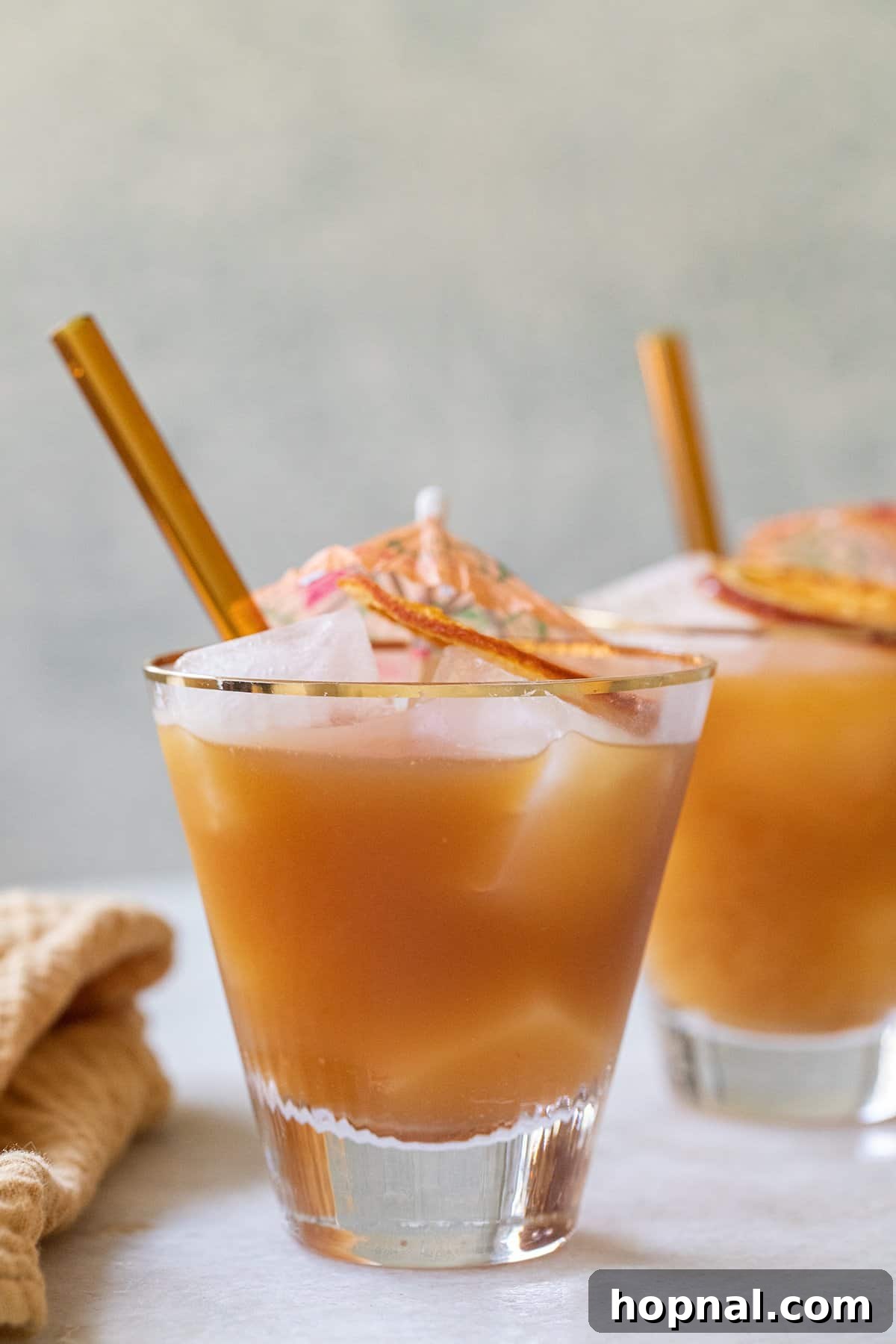 A Brass Monkey drink in a tall glass, garnished with an orange slice and a small cocktail umbrella, set against a bright, inviting background.
