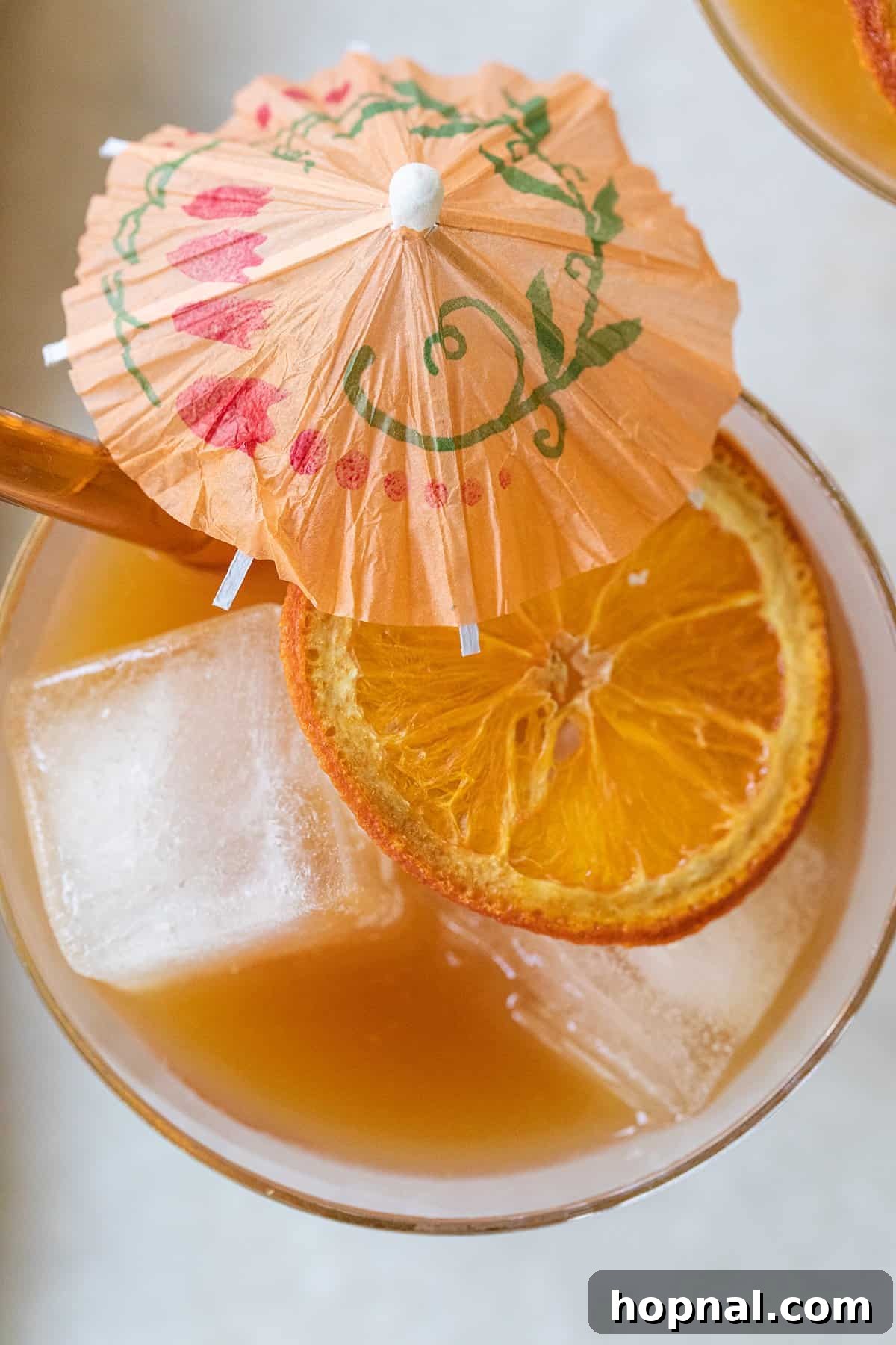 A festive tropical cocktail with an orange slice and a tiny umbrella, embodying vacation vibes.