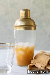 Rum, orange juice, and vodka being added to a cocktail shaker filled with ice.