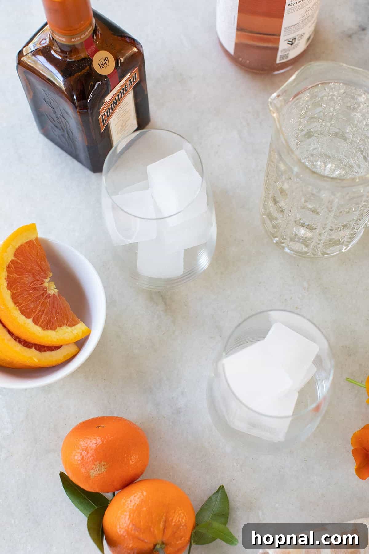 Effortless Rosé Refresher 3 Close-up of the three essential ingredients: rosé wine, sparkling water, and orange liqueur, arranged on a surface.