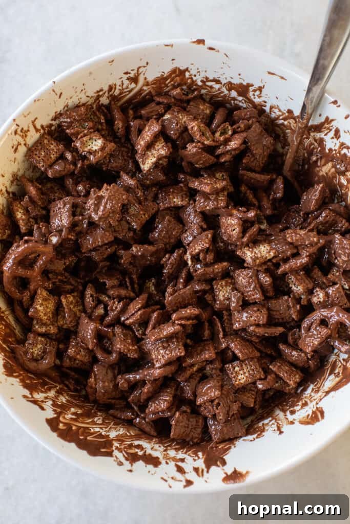Magic Reindeer Dust 7 Close-up view of the Chex cereal and pretzels becoming thoroughly coated in the rich chocolate mixture, ready for the next step of making reindeer food.
