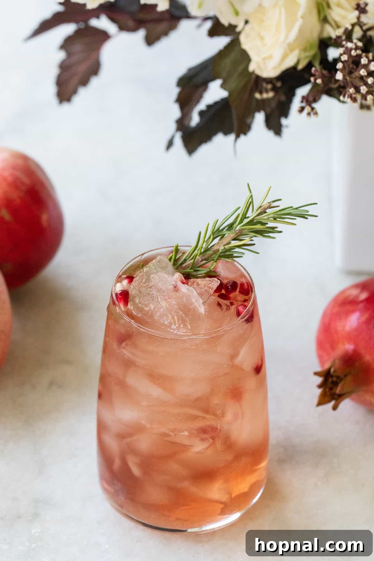 Festive Prosecco Fizz 7 Red cocktail with pomegranates and rosemary in a glass, ready to be enjoyed.