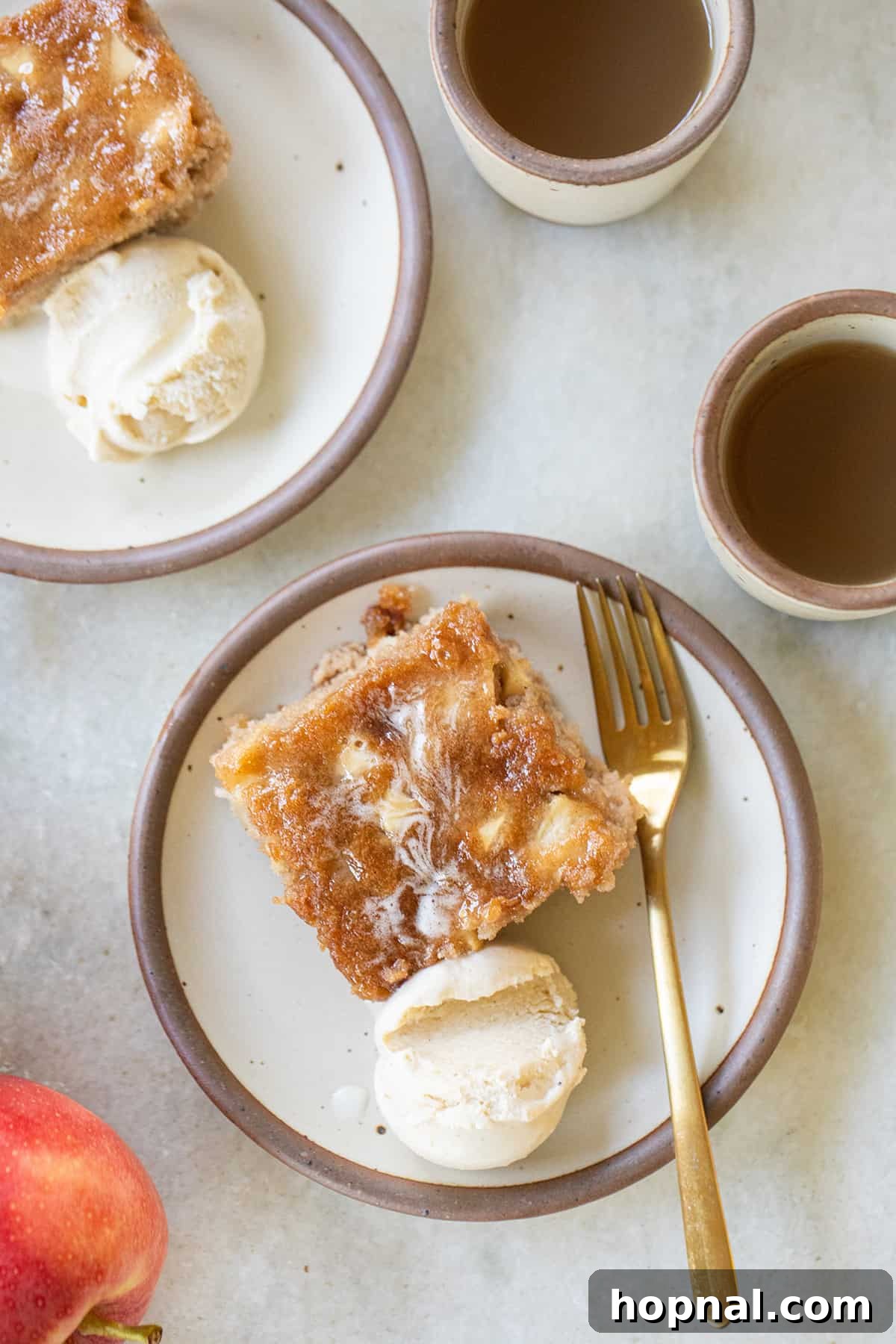 A generous slice of old-fashioned apple cake on a white plate, served alongside a scoop of creamy vanilla ice cream, ready to be enjoyed.