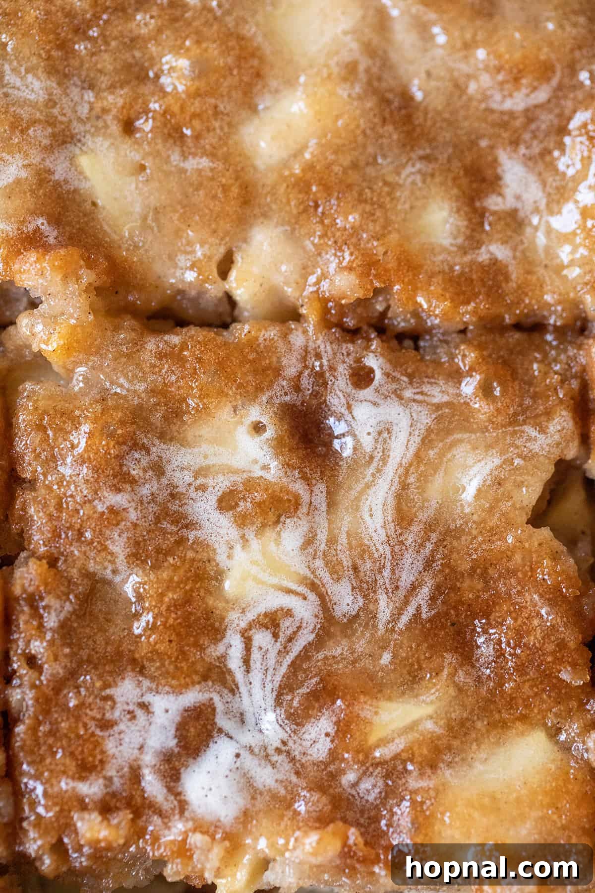 A stunning top-down view of an old-fashioned apple cake, generously covered in a glossy, buttery apple cider glaze, highlighting its moist texture and inviting aroma.