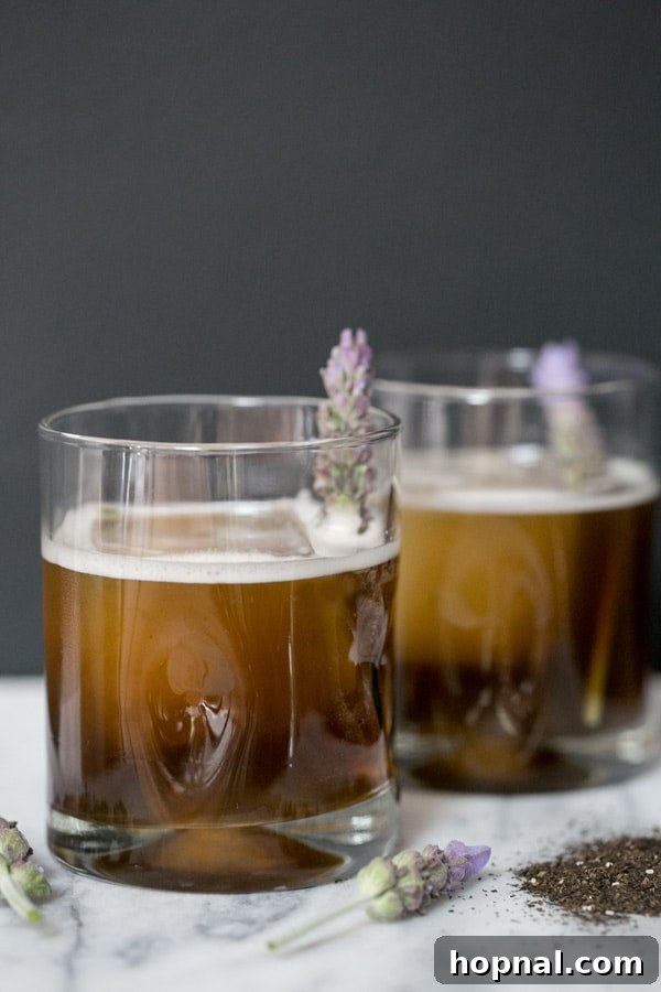 Two Earl Grey tea cocktails in elegant glass tumblers, garnished beautifully.