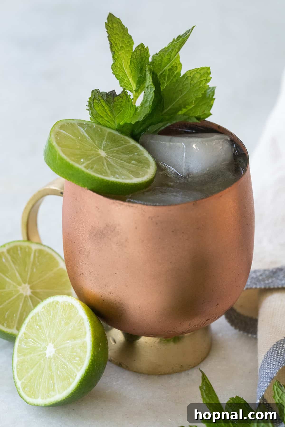 A vibrant bourbon mule in a copper mug, garnished with multiple lime wheels and a fresh mint sprig.