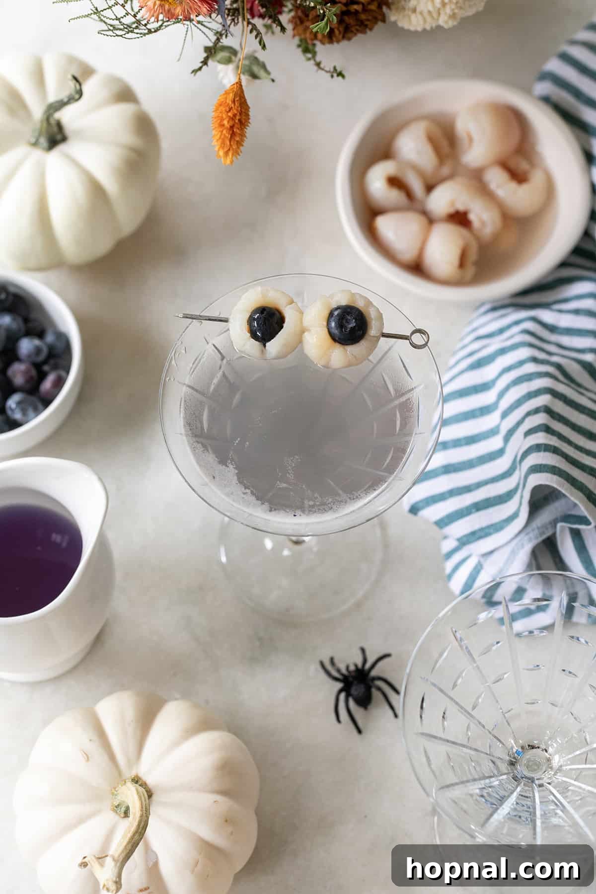 Lychee martini in a martini glass with spooky eyes, perfect for Halloween.