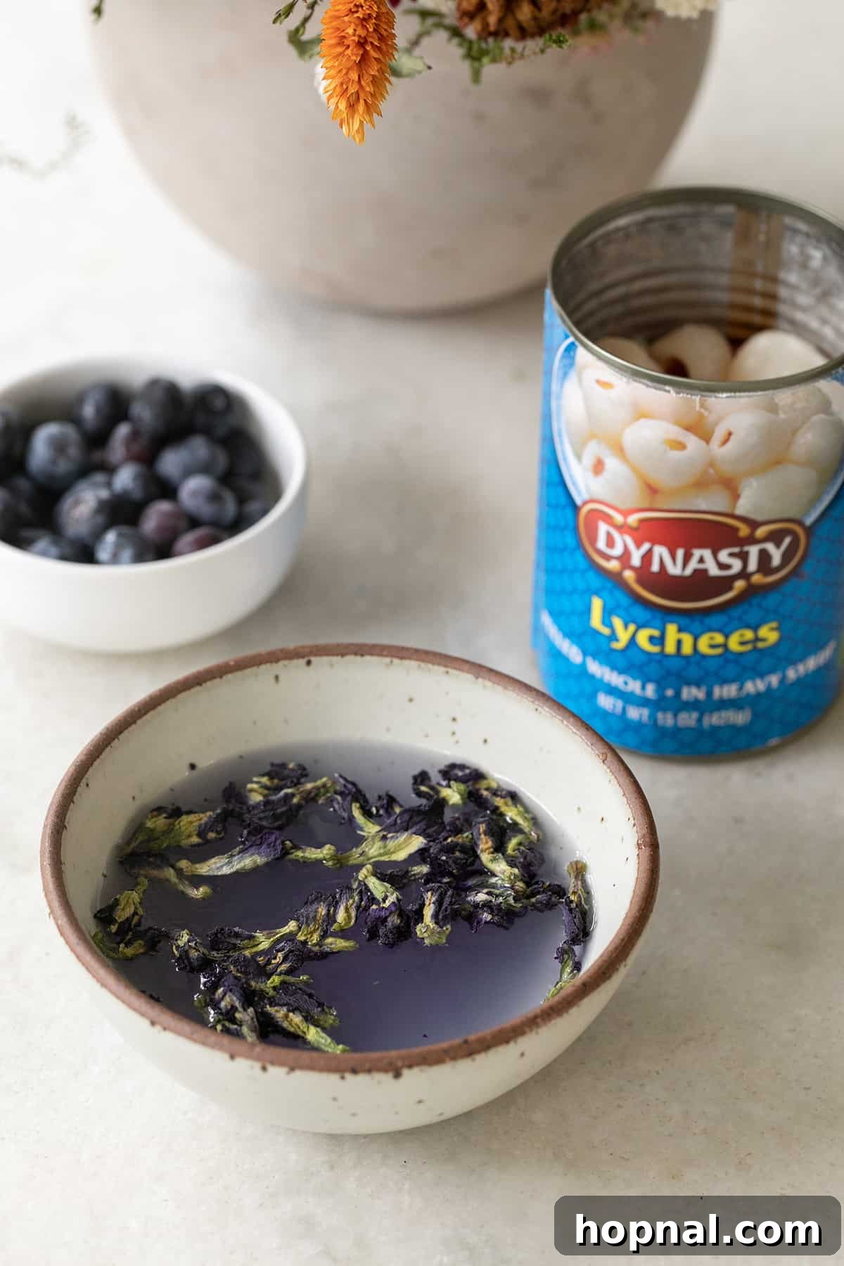 Ingredients for a purple lychee martini: purple vodka, canned lychee, and blueberries.