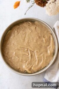 Upside down apple cake batter spread evenly over the top of apples.