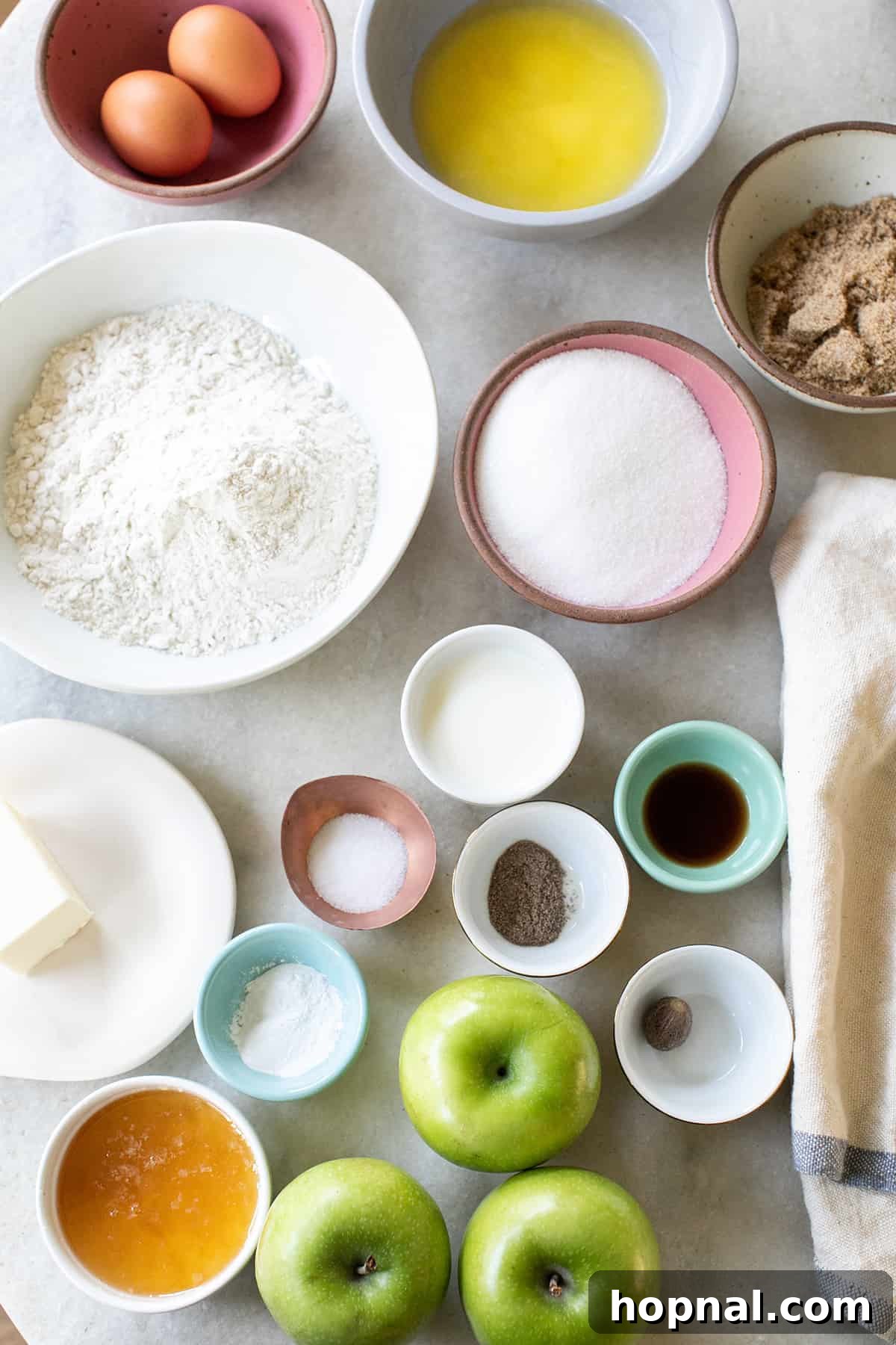 A collection of fresh baking ingredients in individual bowls, ready to be combined for an apple upside-down cake. Flour, sugar, spices, and butter are neatly arranged, hinting at the delicious process to come.
