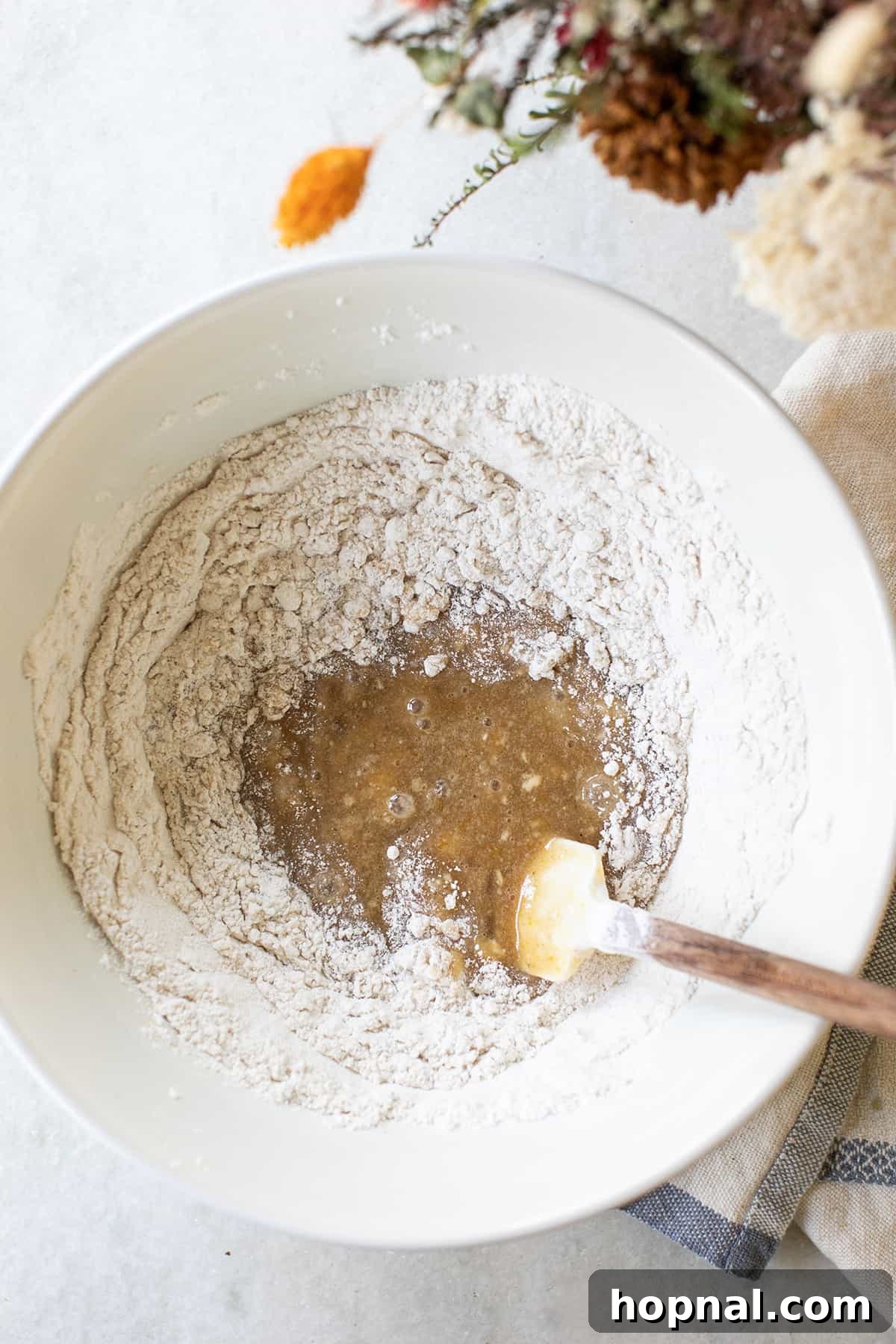 Close-up of fluffy cake batter in a mixing bowl, ready to be spread over the prepared apple base. The texture is light and smooth, hinting at the moistness of the finished apple upside-down cake.