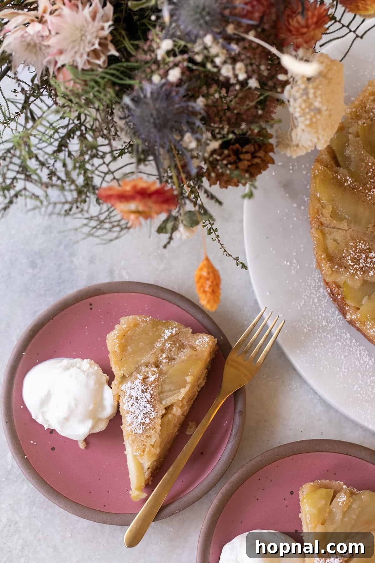 A perfectly portioned slice of apple upside-down cake on a white plate, showcasing its golden caramelized apples and tender cake layer. A fork rests beside it, inviting a delicious taste.