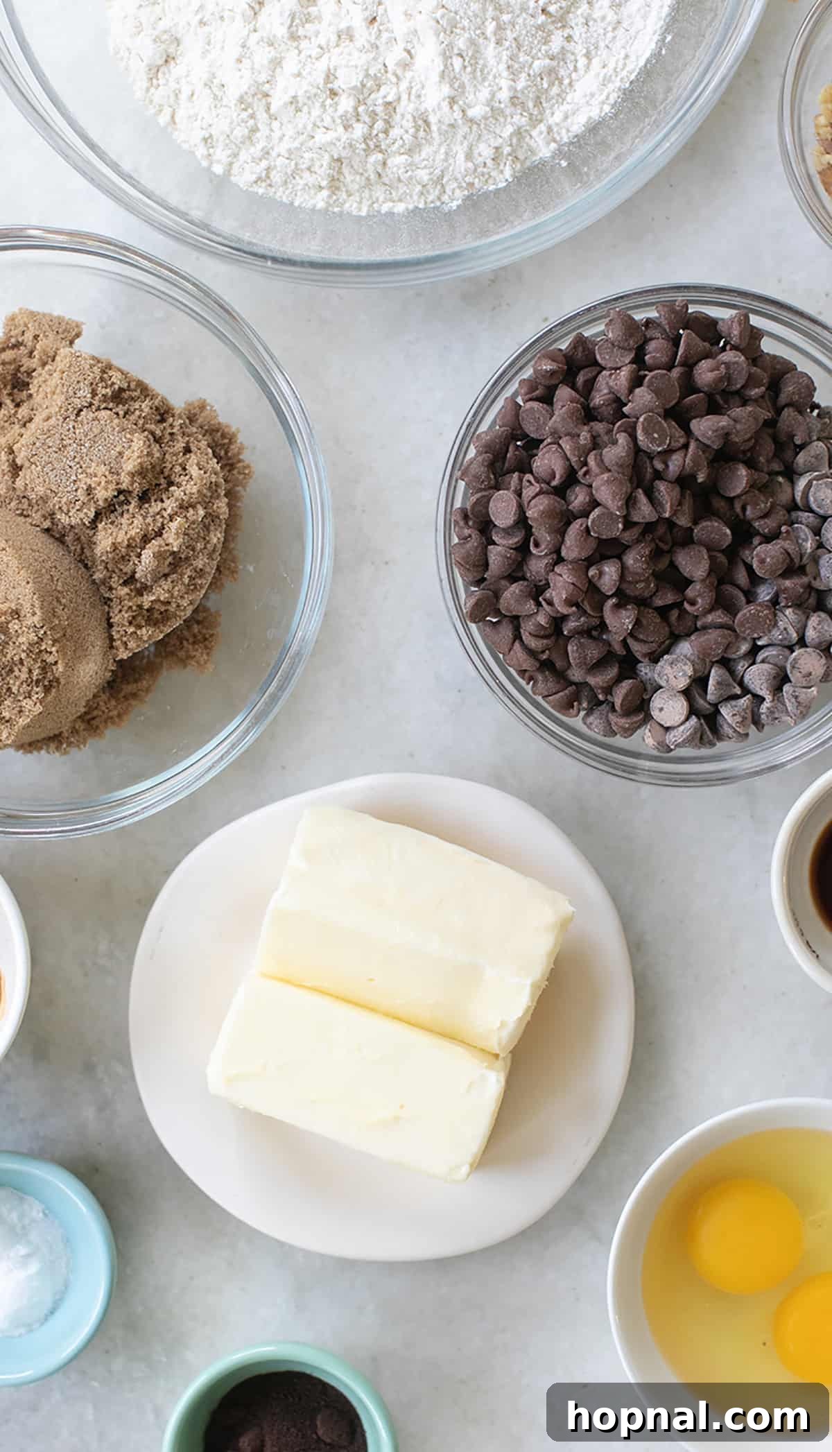 High-quality ingredients for baking espresso cookies, including butter, chocolate chips, brown sugar, flour, and eggs, arranged in separate bowls.