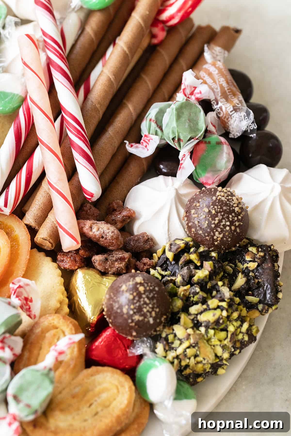A vibrant Christmas dessert platter loaded with cookies, chocolate truffles, candy canes, and a variety of holiday candies.