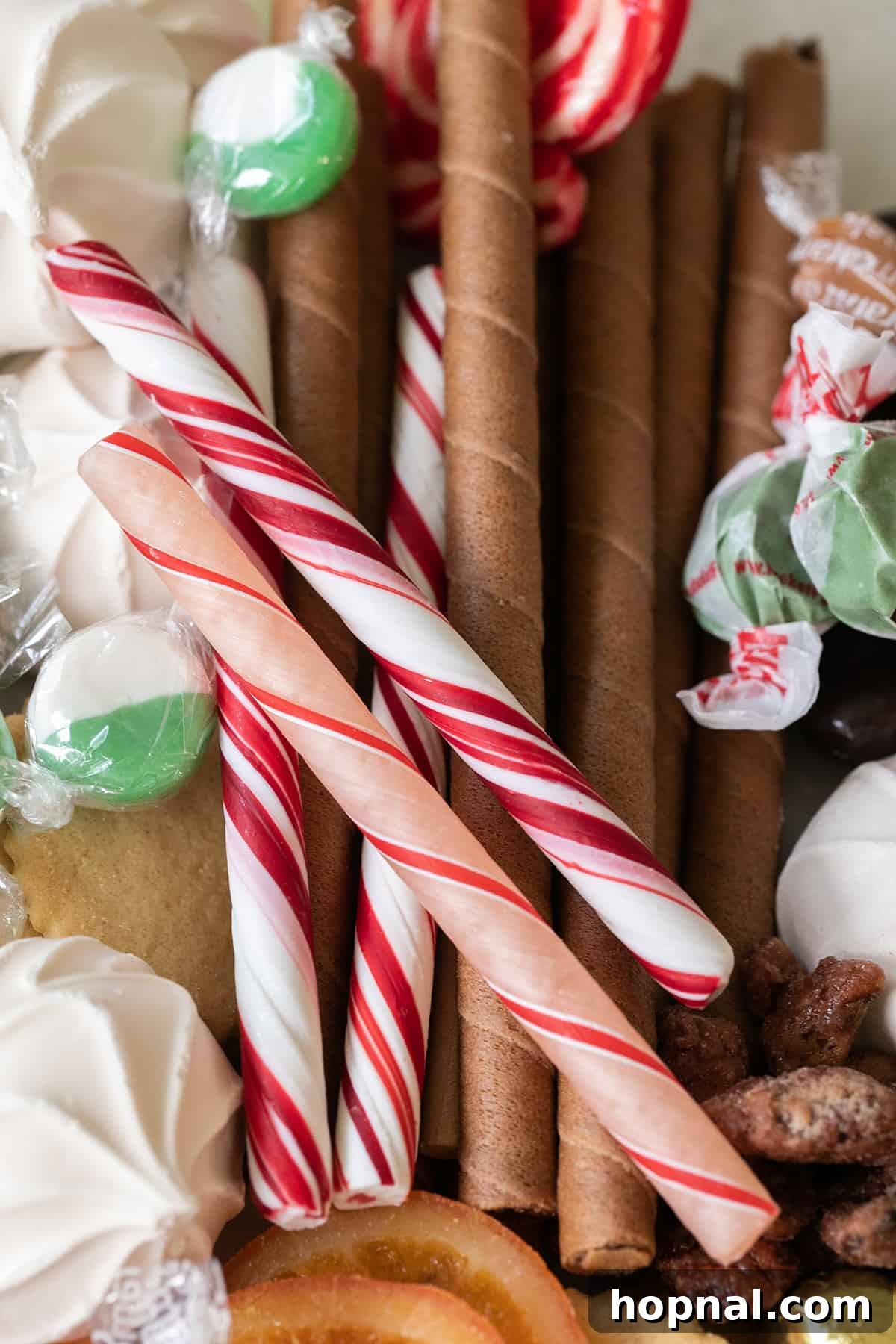 A close-up of wafer cookies and candy canes arranged on a festive holiday dessert platter, showcasing texture and color.